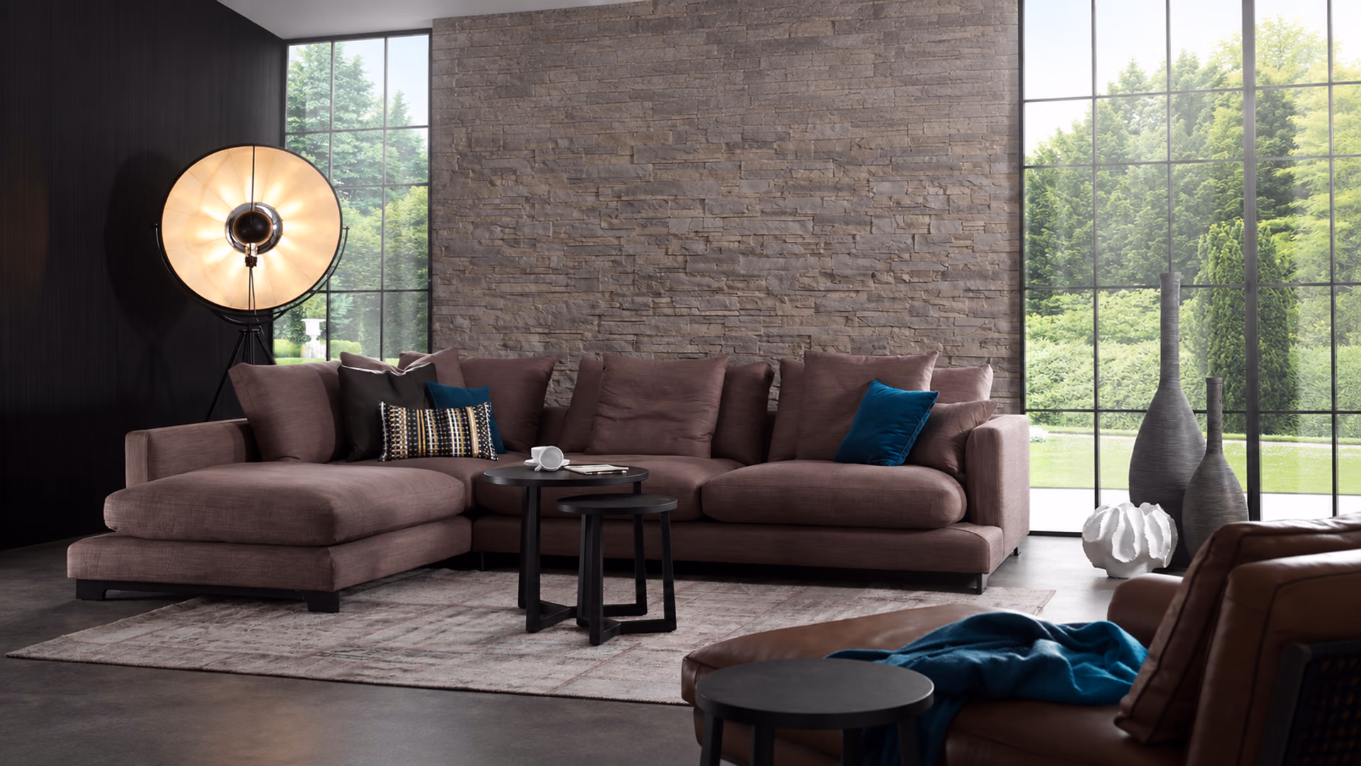 Camerich Lazytime sectional in muted plum upholstery beside tall windows and a textured stone wall.