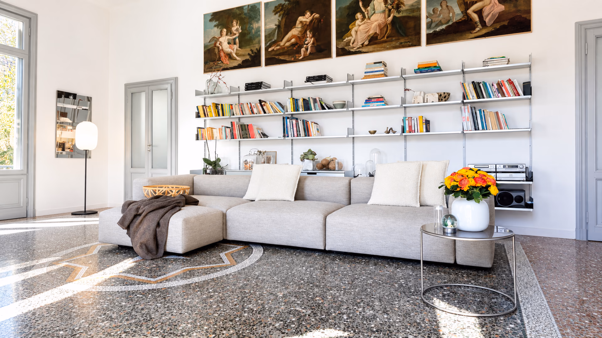 Cappellini Oblong Plus modular sofa beneath open bookshelves in a light-filled living room.