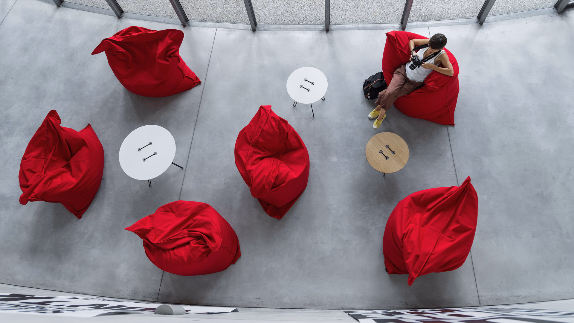 Casamania red soft lounge seats and button-shaped side tables in an open concrete interior.