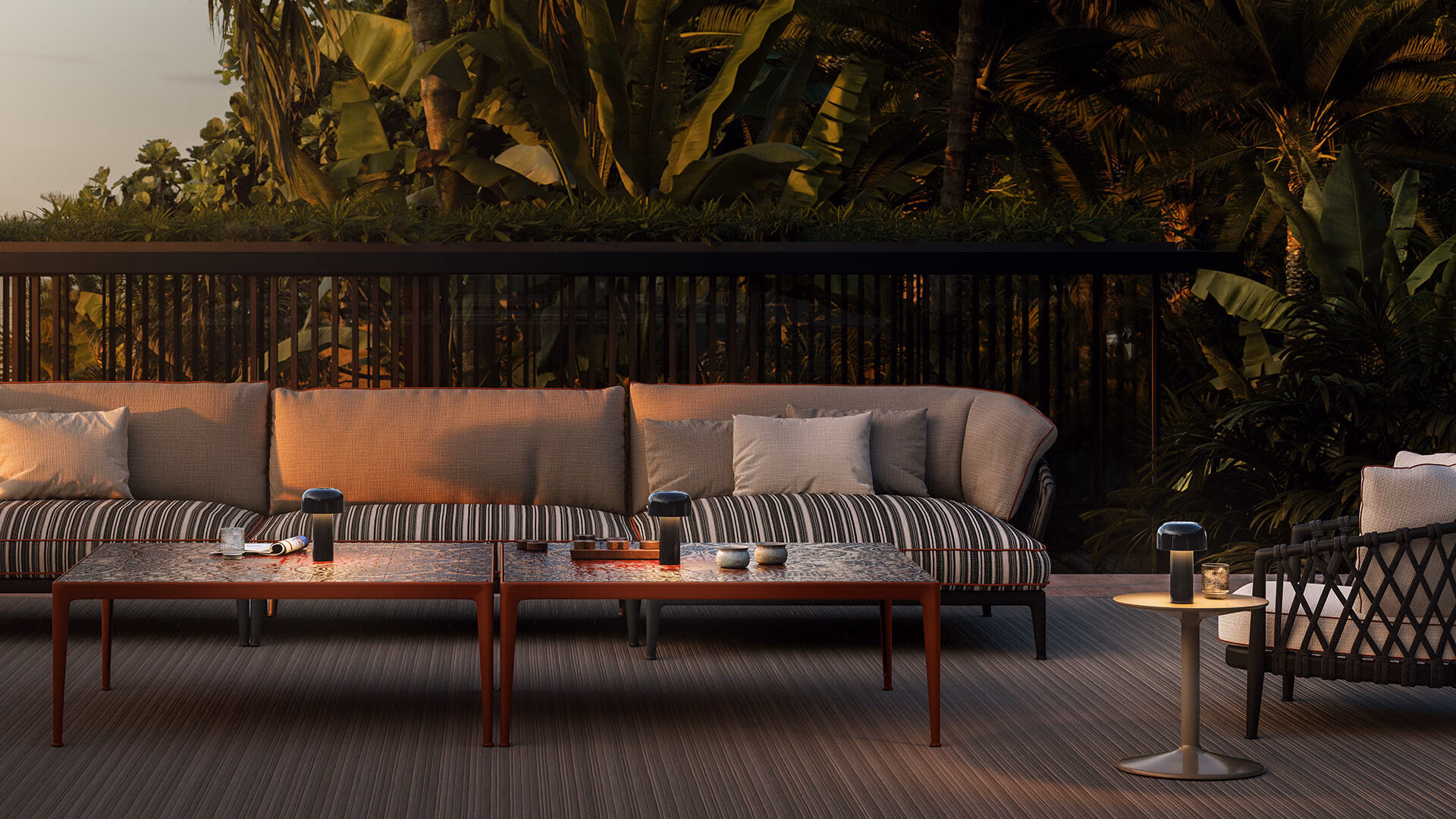 Flos Bellhop portable lamps lighting tables on a leafy outdoor terrace at night.