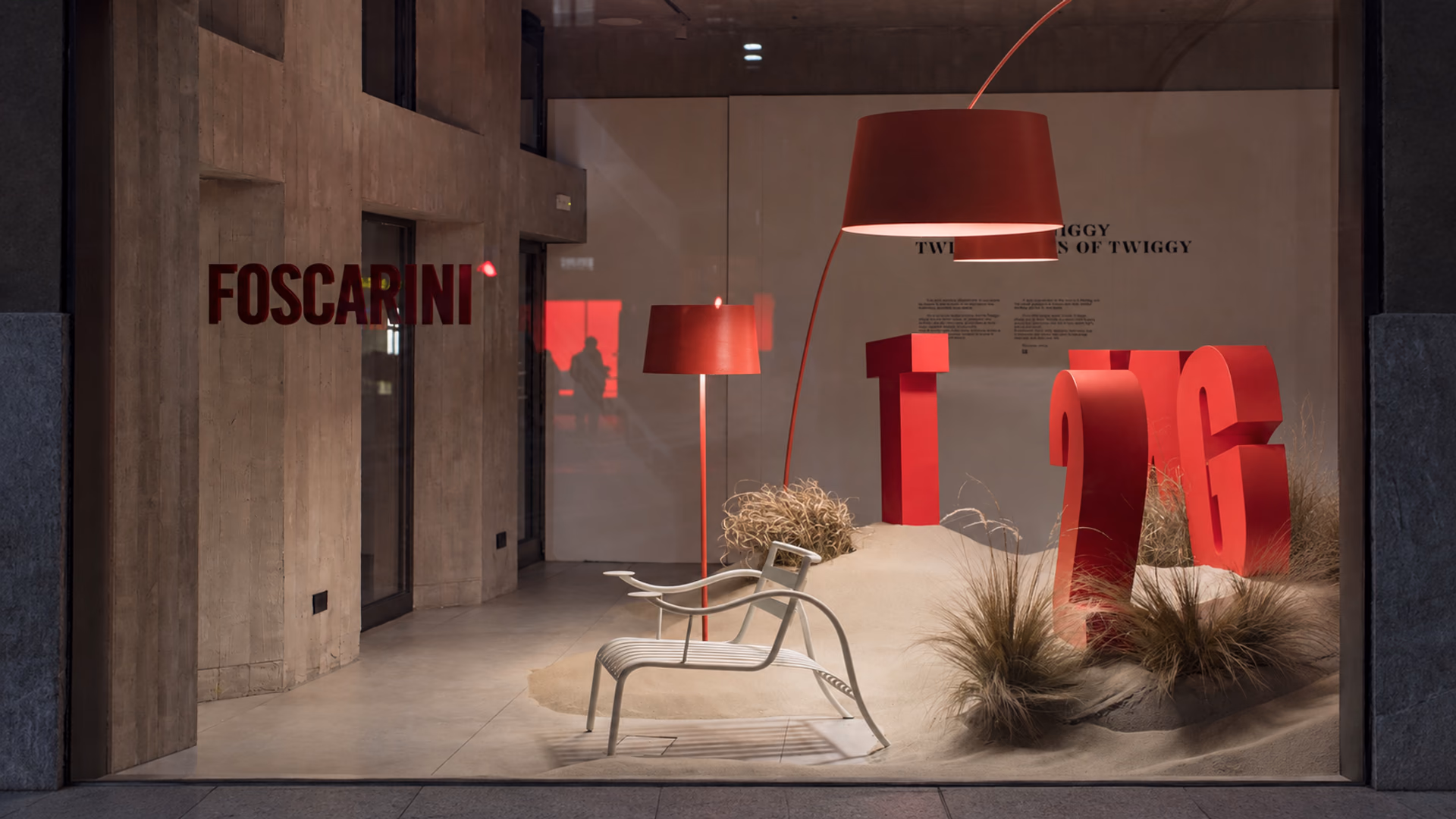 Red Foscarini Twiggy floor lamps in the brand's display with sculptural red lettering and pale seating.