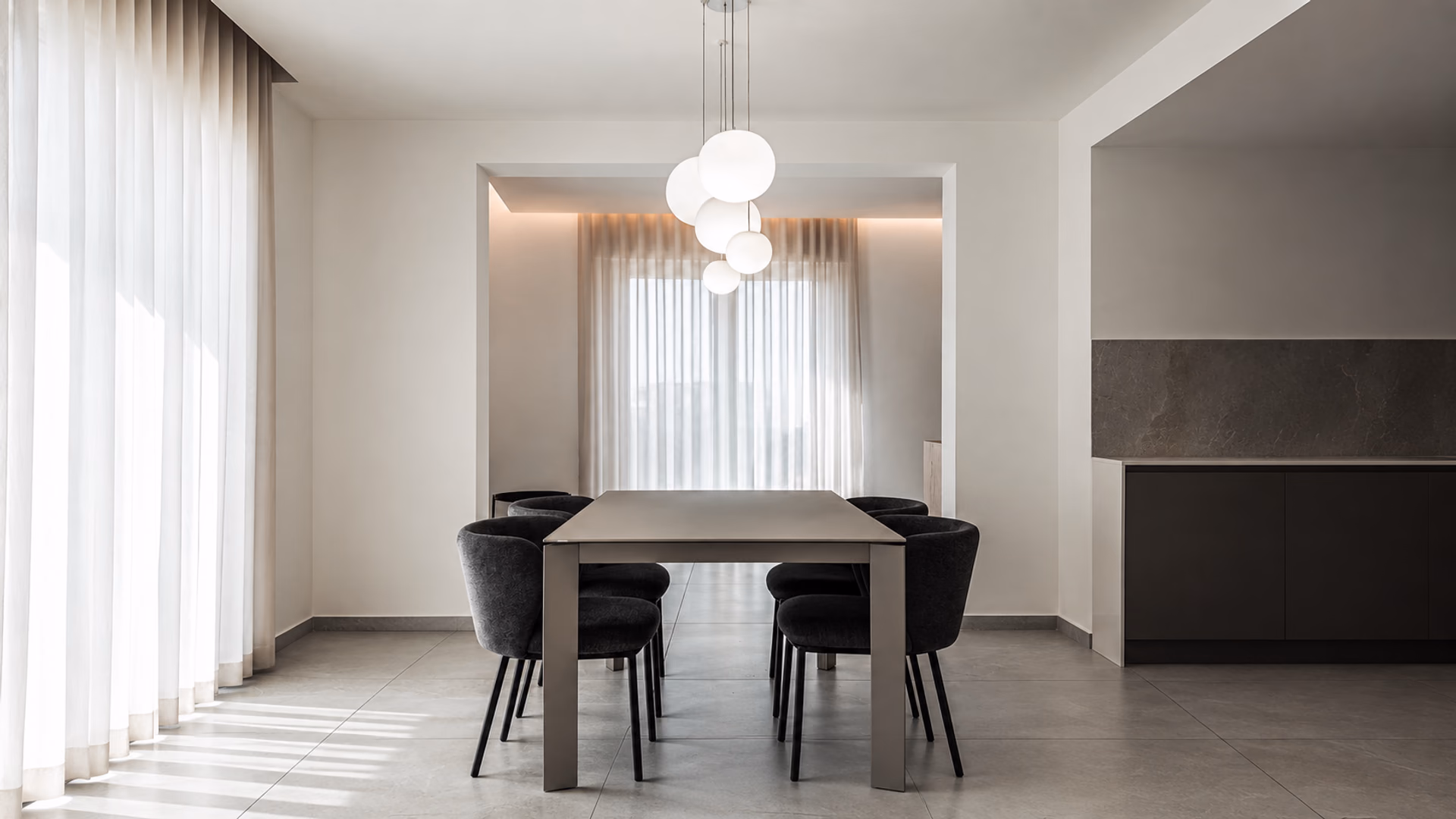 White Lodes globe pendants above a dark dining table and upholstered chairs