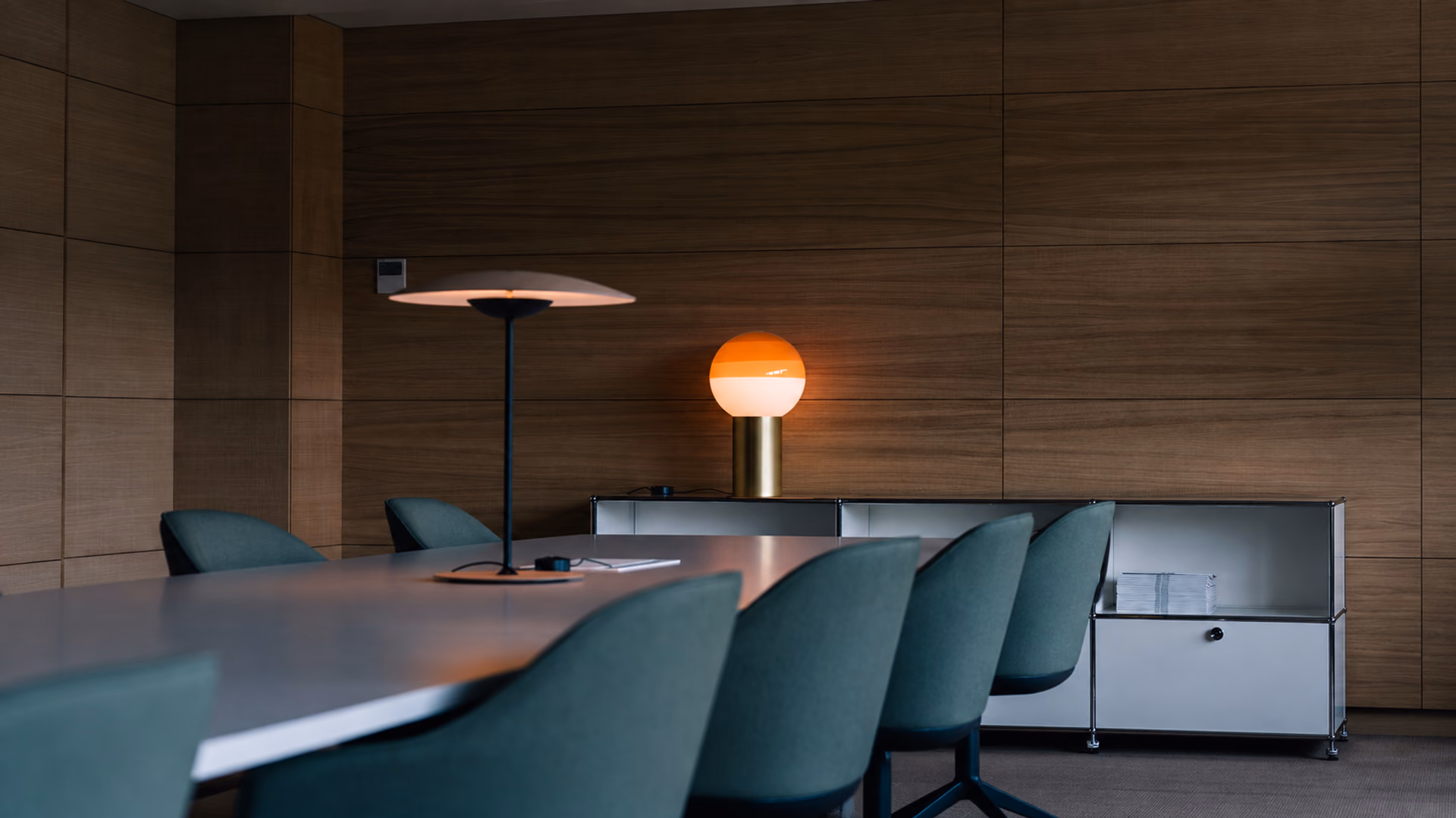 Orange Marset Dipping Light table lamp in a meeting room with green chairs