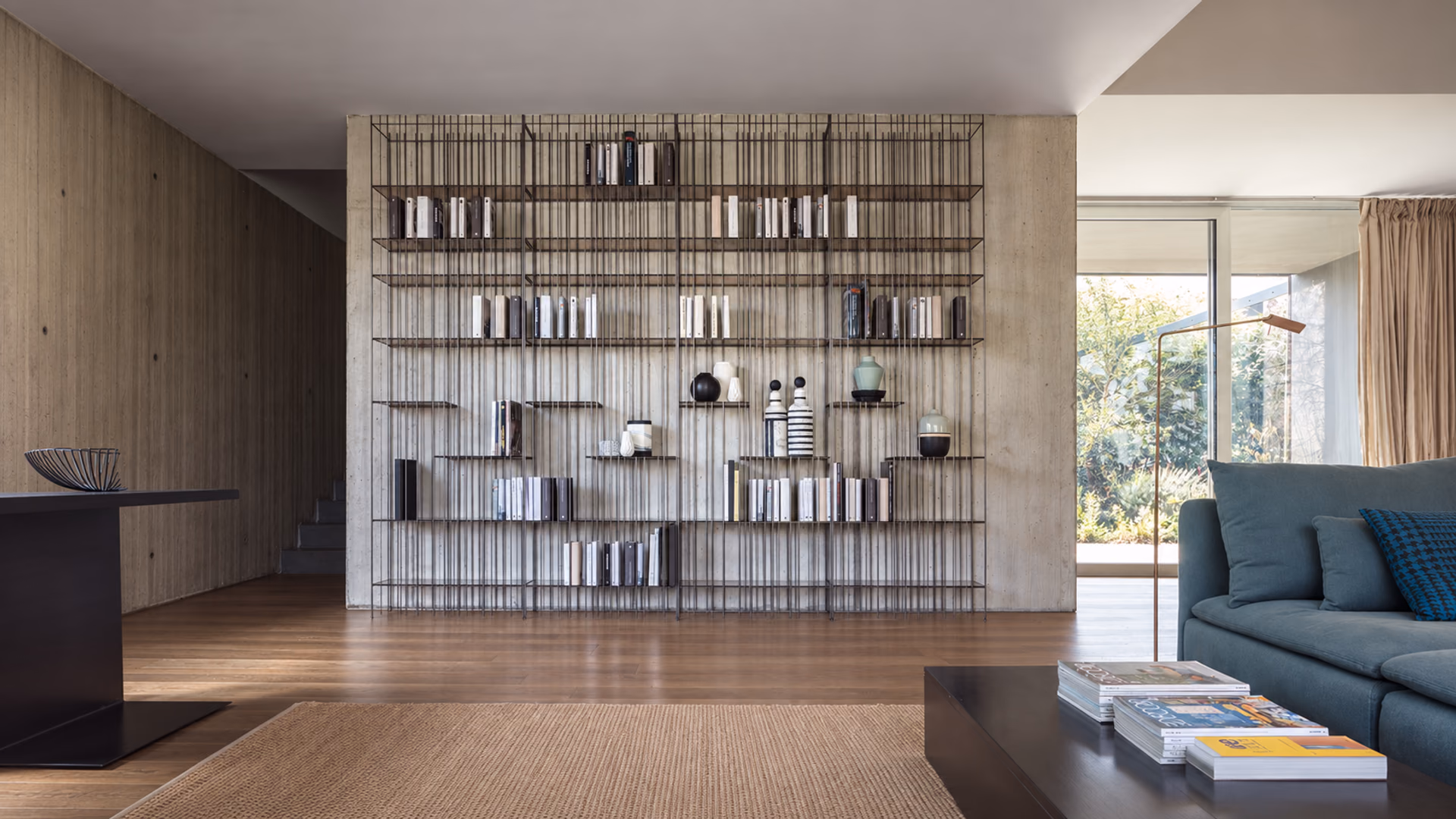 Mogg Metrica metal bookcases displaying books and objects beside a blue sofa