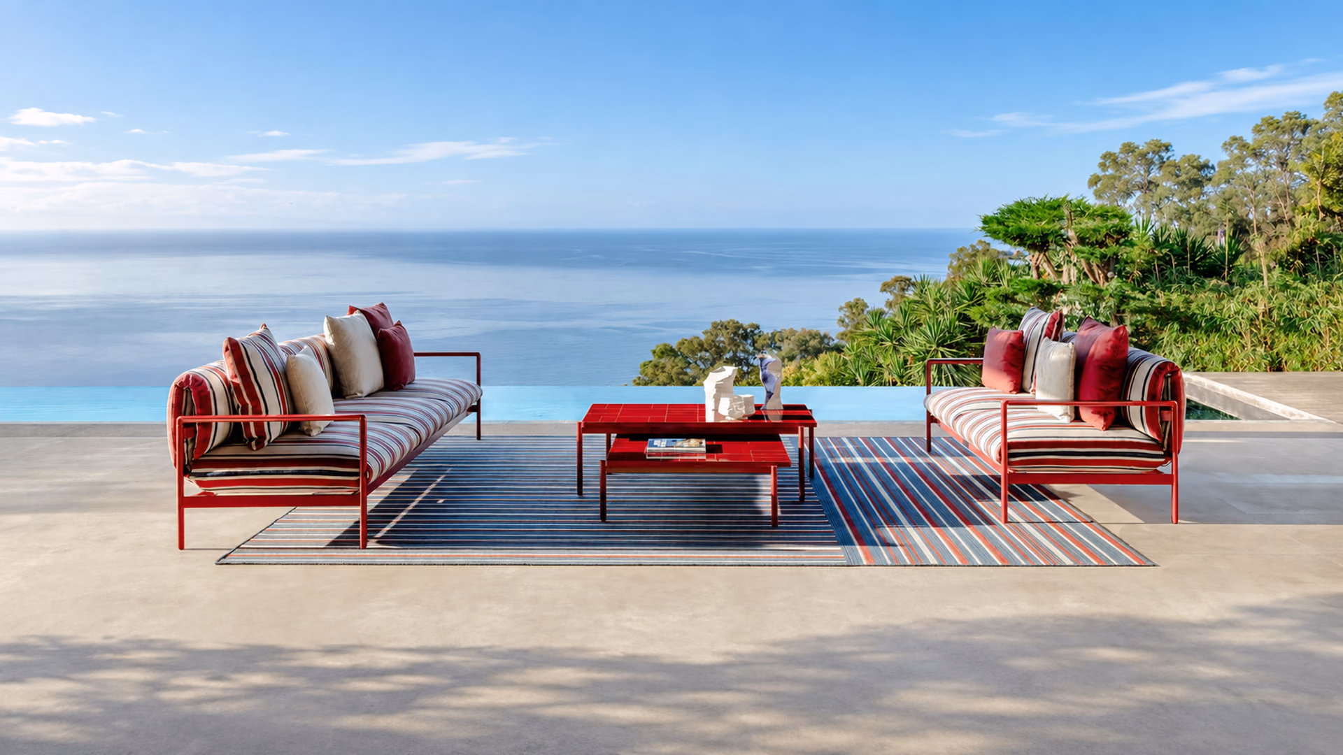 Talenti Nalu outdoor sofas with red frames and striped cushions on a coastal terrace
