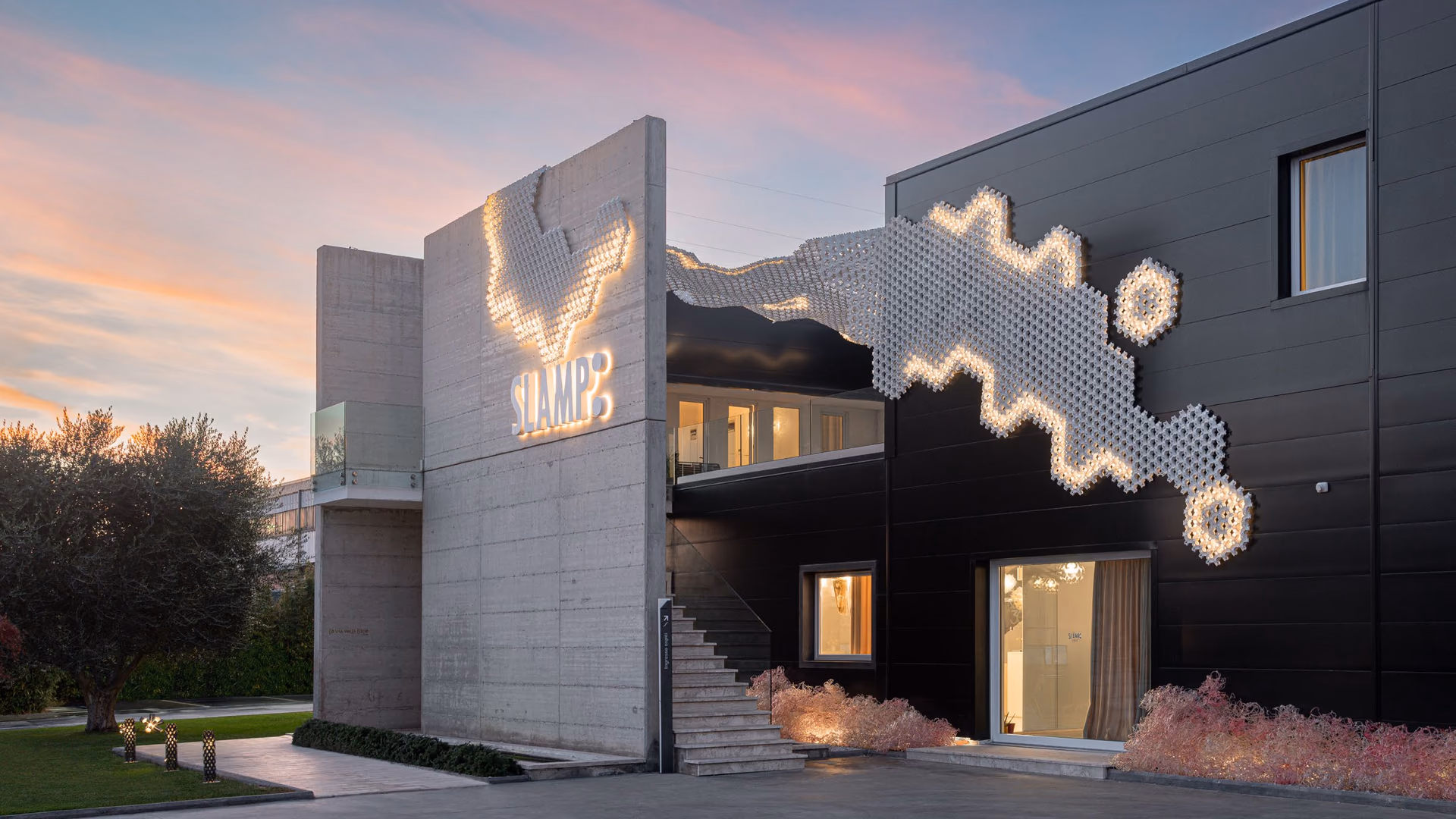 Slamp Nuvem outdoor modules glowing across a dark building façade at dusk