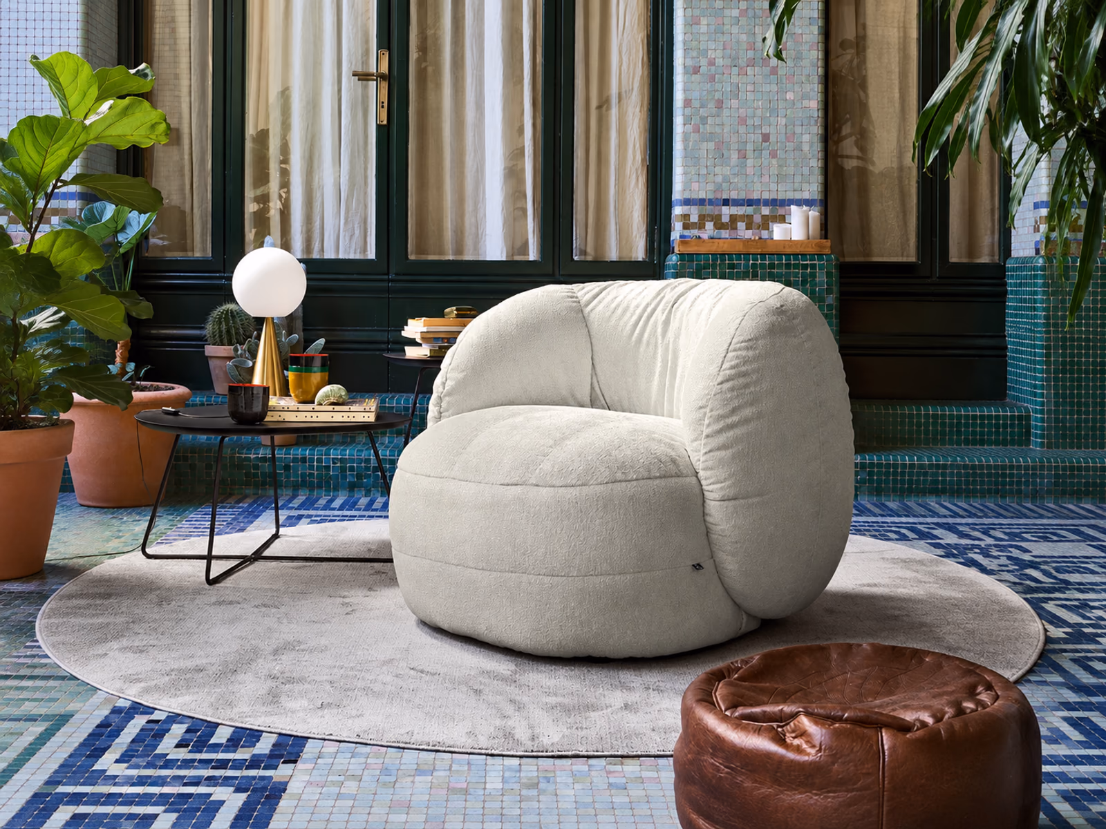 Connubia: A white Ciop armchair sits among plants, patterned tiles and a compact side table.