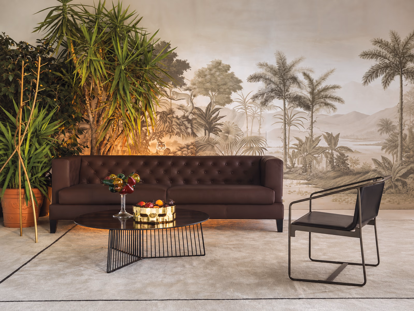 Driade: A brown Hall sofa stands against botanical wallpaper, paired with a round coffee table and slender lounge chair.
