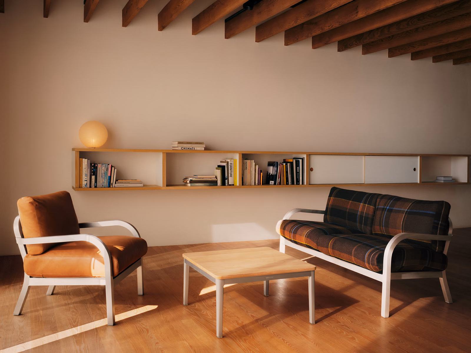 Emeco: A Navy Lounge three-seat sofa is shown with dark patterned upholstery in an interior setting.
