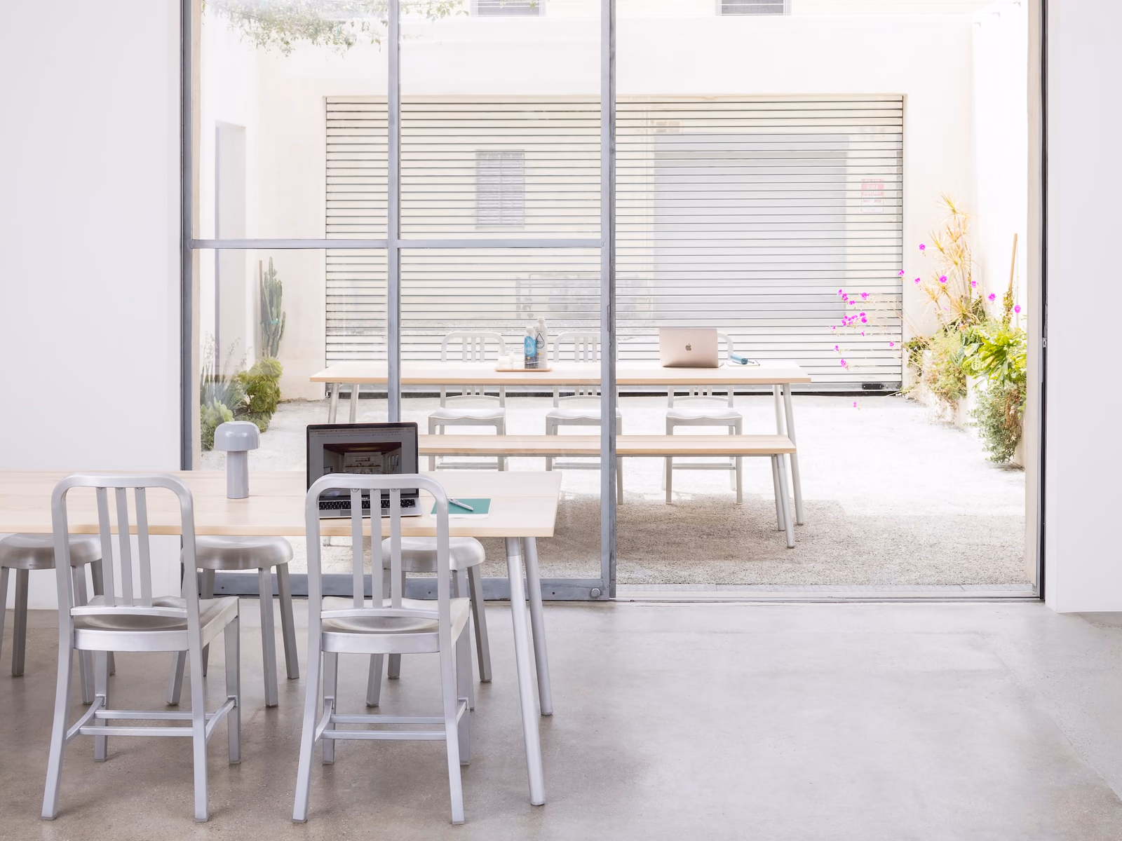 Emeco: Navy chairs create a compact seating arrangement in a bright interior with glazed partitions.