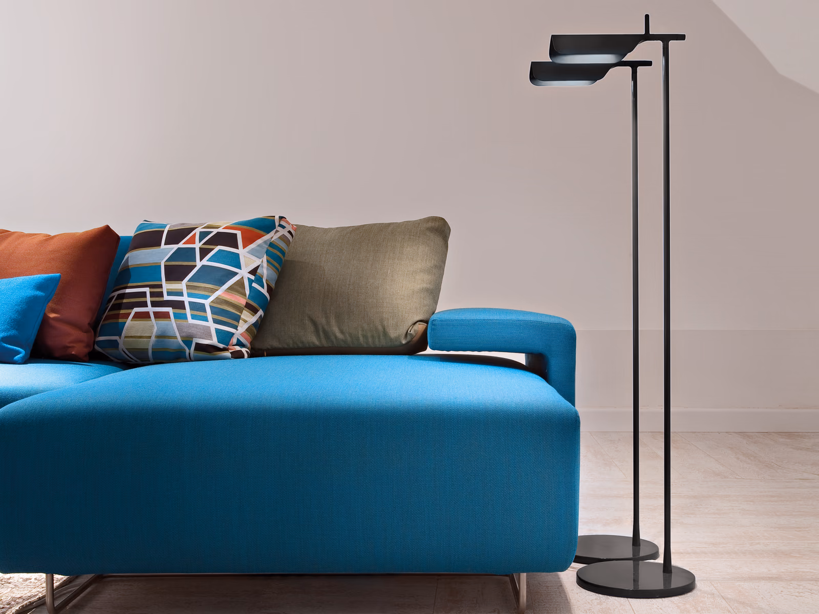 Flos: A Tab floor lamp provides a compact lighting accent beside a blue sofa.