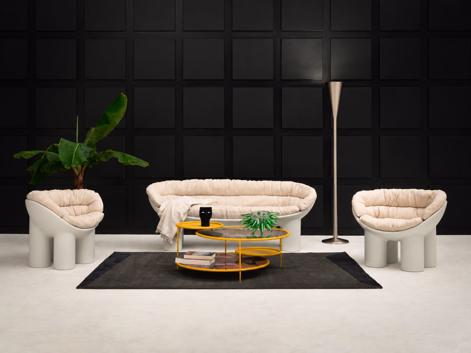 Fontana Arte: A Luminator floor lamp stands beside pale sculptural seating against a dark paneled wall.