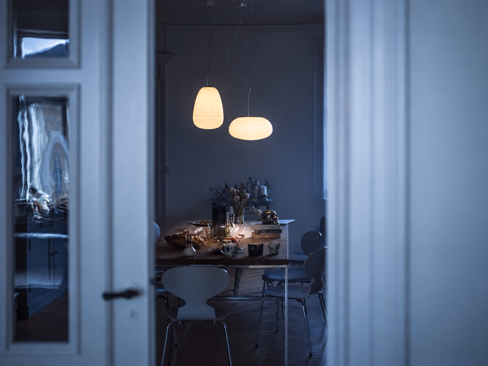 Foscarini: Rituals lighting is shown in a dining room viewed through a doorway.