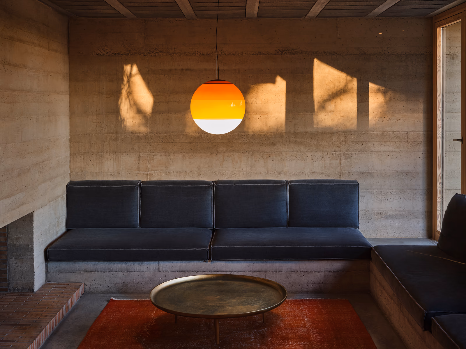 Marset: A Dipping Light pendant adds warm color above a blue sofa.