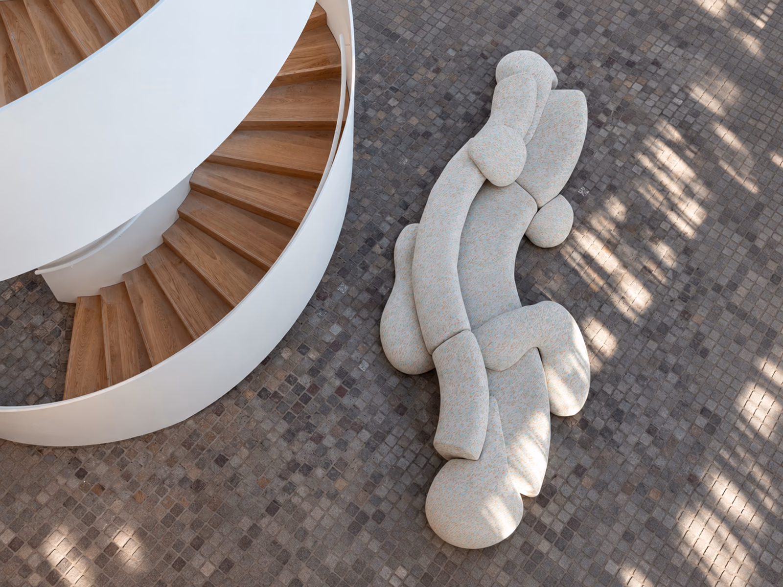 Moroso: A pale Gruuvelot sofa forms an organic seating composition beside a curving staircase.