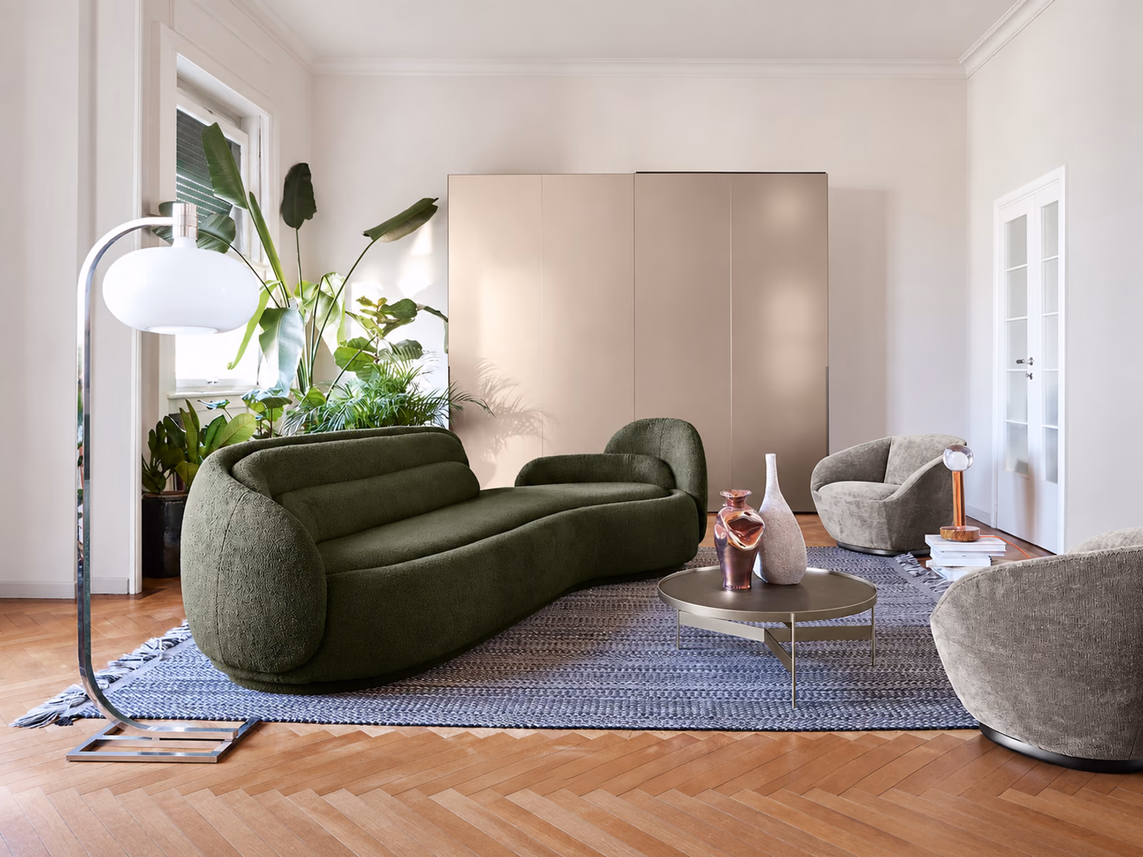 Pianca: A green Peonia sofa pairs with pale armchairs and a round table on a blue rug.