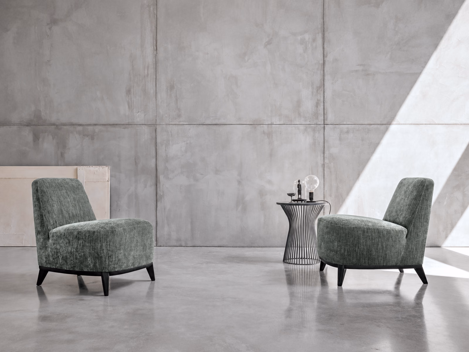 Tomasella: Two green Loft chairs face a slender occasional table against a concrete wall.